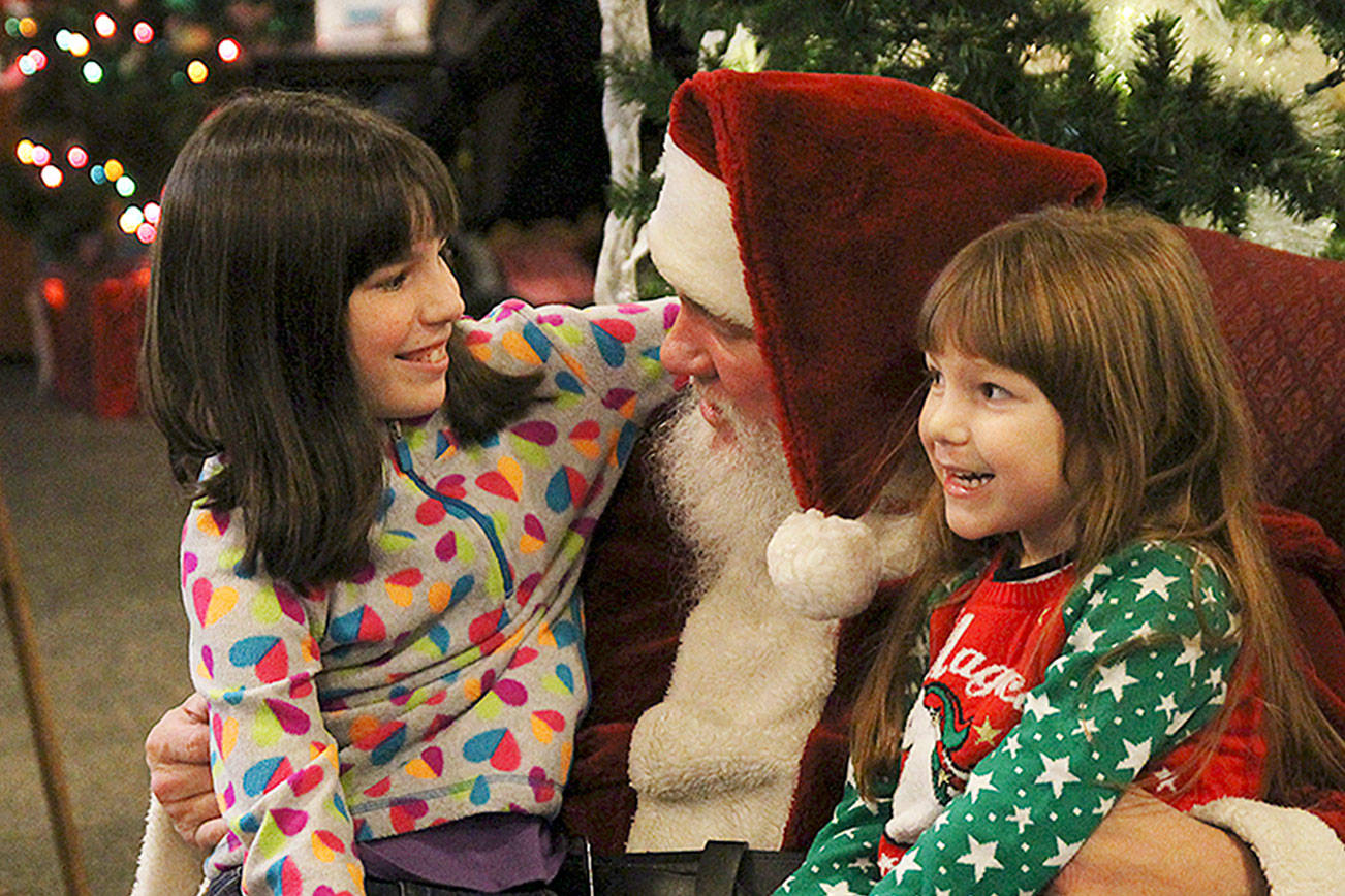 Photo by Laura Guido/ Whidbey News-Times.                                During Oak Harbor’s celebration on Pioneer Way Saturday, Tracy, 10, and Katelyn, 5, tell Santa Claus what they want for Christmas this year. He regrettably informed them he cannot give live animals.