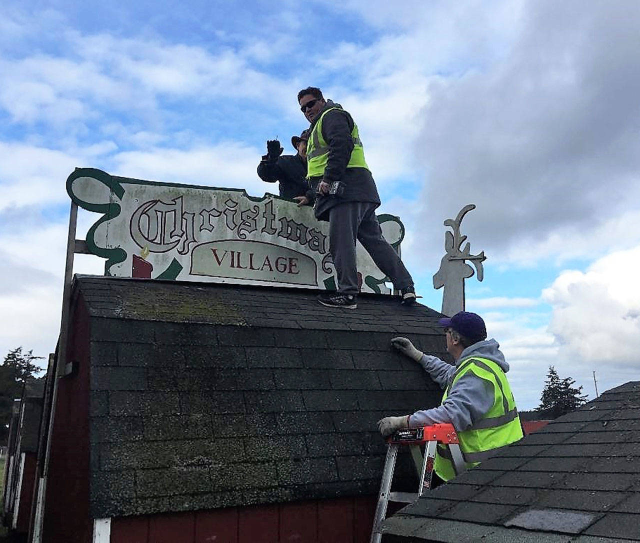 Photo provided.                                Top background, Rogers Wisniewski, Dean Cox and Bob O’Dell secure the Christmas Village sign.