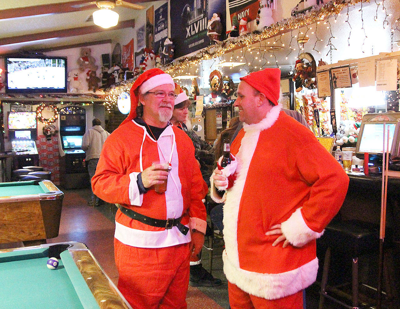 Mike Jackets, left, and Jason Lacey take part in a crucial aspect of the Santa pub crawl tradition. Photo by Laura Guido/Whidbey News-Times