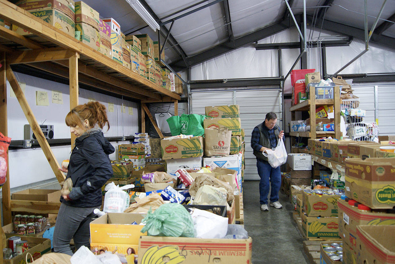 Photo by Maria Matson/Whidbey News-Times.                                Sonya Wallace, left, sorts through canned goods, searching for the best place to put each item. Brad Trimmer, at right, has volunteered at North Whidbey Help House since 2012.