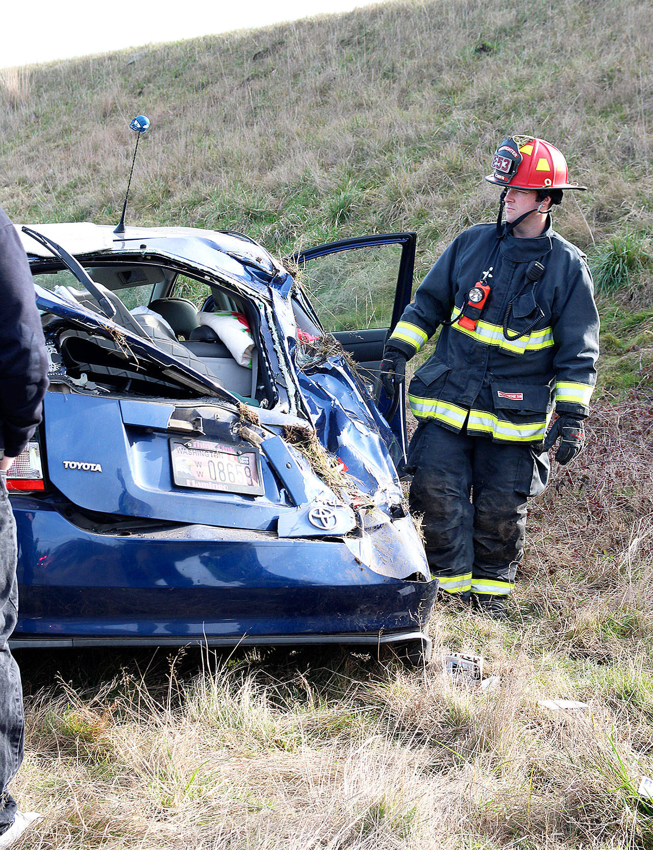 Central Whidbey Island Fire and Rescue Lt. James Meek inspects damage to a prius after a rollover accident off Highway 20 Monday afternoon. Photo by Laura Guido/Whidbey News-Times