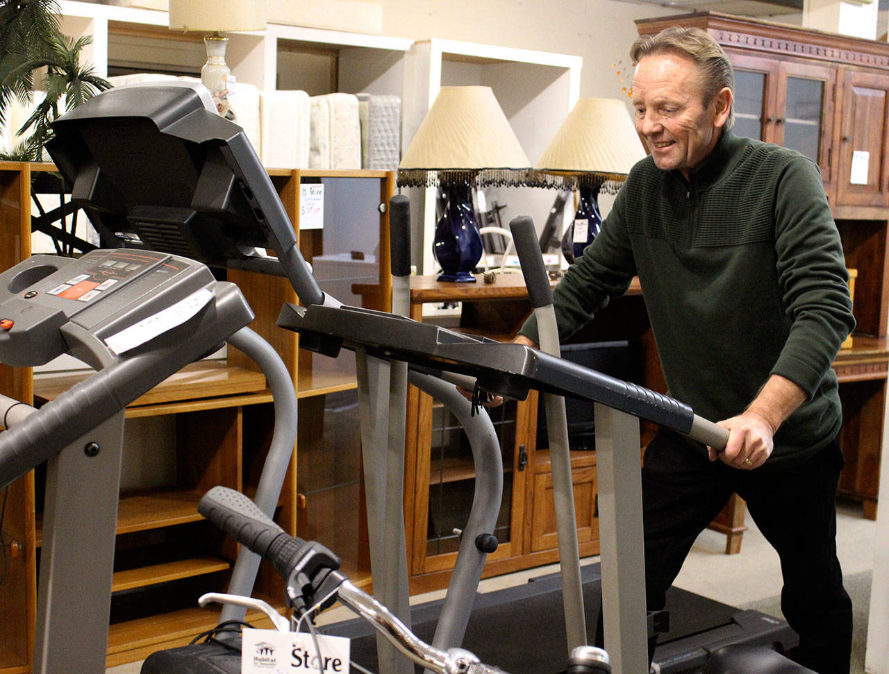 New stores director Tony Persson demonstrates that home exercise equipment is sometimes donated and put up for sale at the Oak Harbor Habitat for Humanity store. (Photo by Patricia Guthrie/Whidbey News-Times)