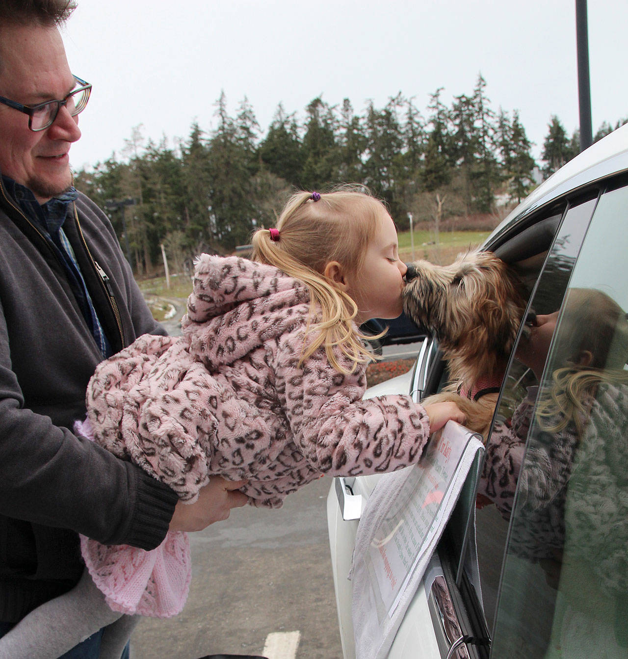 Piper Hedrick leans in for a smooch with popular pooch Katy. Her father, Colin, holds his 3-year-old daughter as she greets Katy.“She loves puppies,” Colin said. He said Piper is good at greeting dogs properly, by holding her hand out gently first for it to sniff. His wife Erin works at Starbucks. (Photos by Maria Matson/Whidbey News-Times)