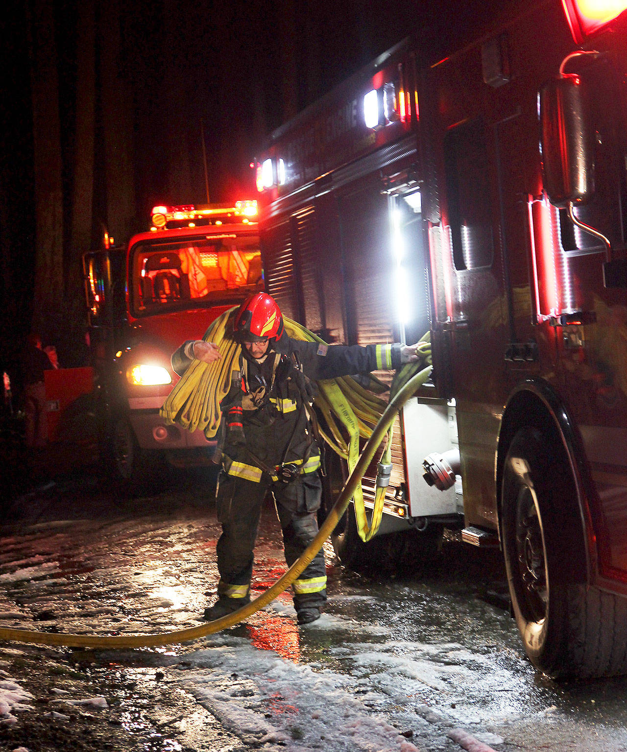 Lt. Marv Raavel, with Central Whidbey Island Fire and Rescue, gathers a hose used to extinguish a residential fire Thursday night in Coupeville. No one was injured, but the home sustained significant smoke damage. Photo by Laura Guido/Whidbey News-Times
