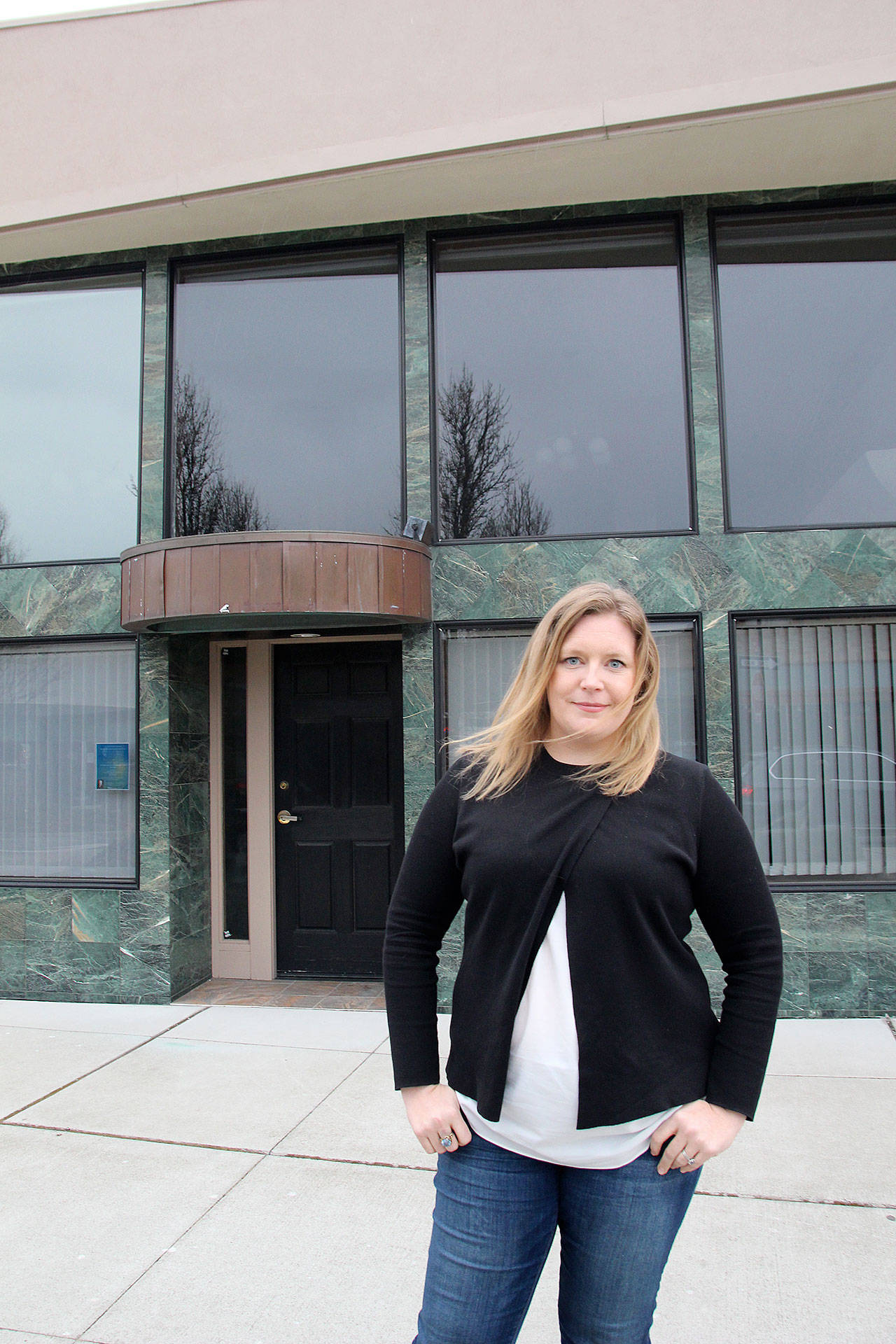 Sarah Schacht stands in front of one of the buildings she owns in downtown Oak Harbor. (Photo by Jessie Stensland / Whidbey News-Times)