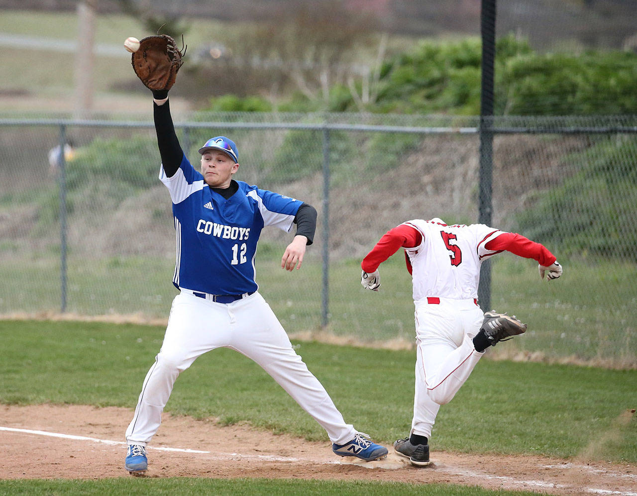 Matt Hilborn beats out an infield hit as Chimacum first baseman Cody Clark makes the catch.(Photo by John Fisken)