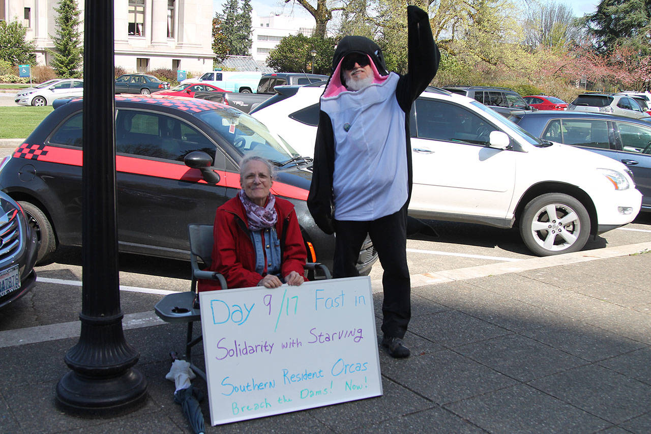 Photo provided. Lanni Johnson sitting in front of the capitol building steps where she has been on a hunger strike for the last 9 days to save the Southern Resident Orcas. Johnson is joined by supporter, Phil Myers, who can be seen in an orca onesie.
