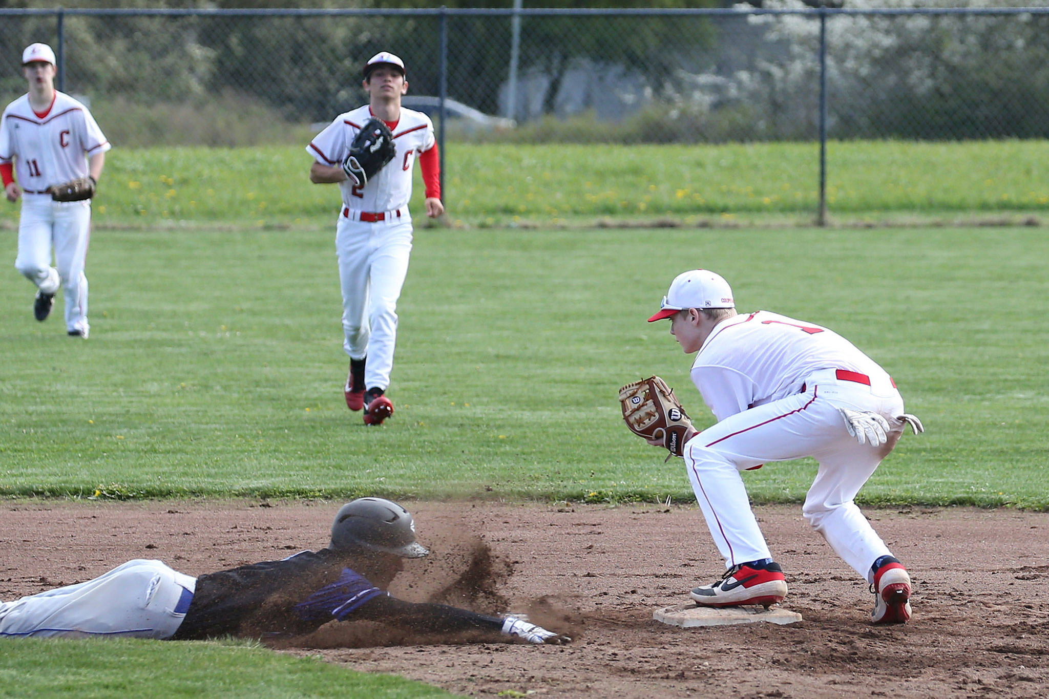 Coupeville second baseman Daniel Olson forces out a South Whidbey runner who failed to tag up on time on a fly ball. Center fielder Hawtorne Wolfe, center, made the catch and throw that doubled off the Falcon.(Photo by John Fisken)