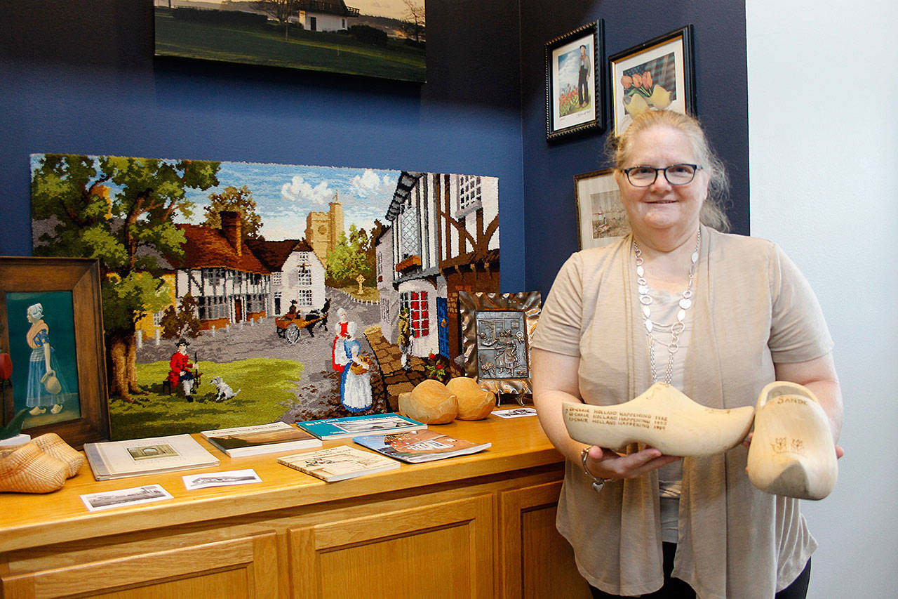 Events Manager Vicki Graham holds an oversized pair of Dutch wooden shoes. In the background are Holland Happening- related items lent for display by the community.                                (Photo by Maria Matson)