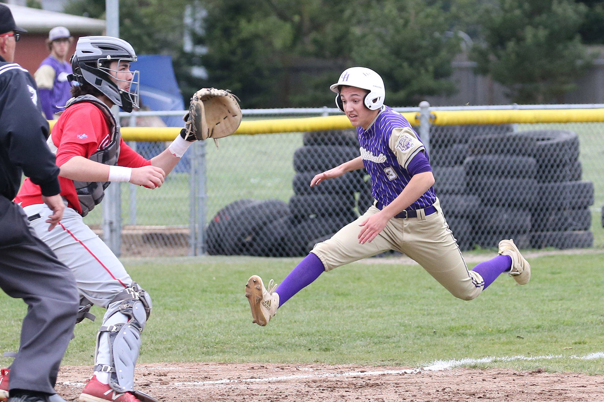 Oak Harbors Andrew Dixon races home to score on a sacrifice fly as Stanwoods Braden Joyner awaits the throw.(Photo by John Fisken)