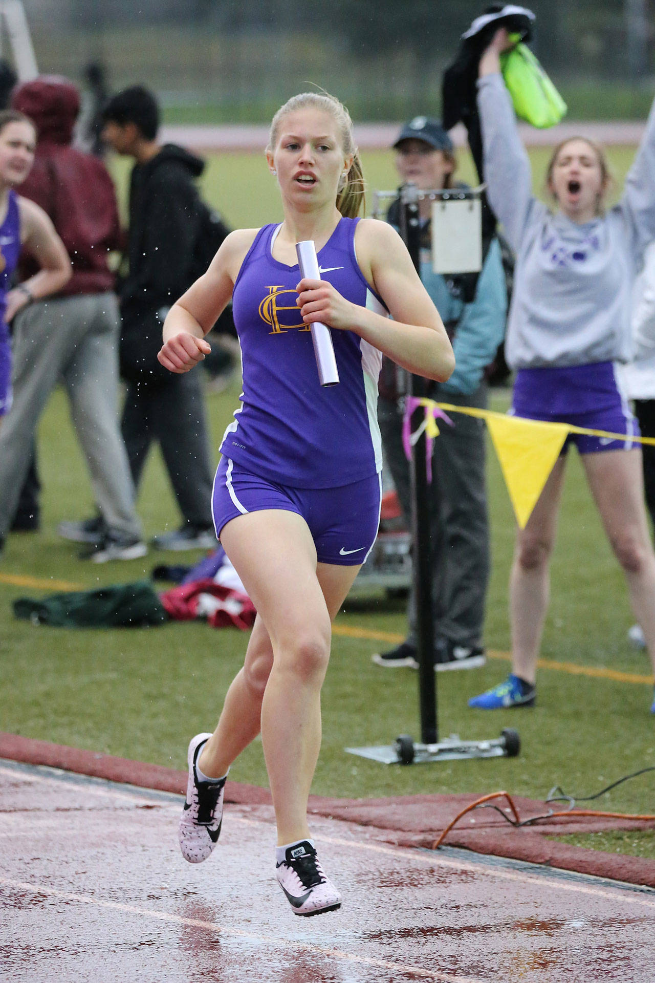 Natalie French helps Oak Harbor win the 4x400 relay as Brenna Rothman (background), who ran an earlier leg, cheers her on.(Photo by John Fisken)