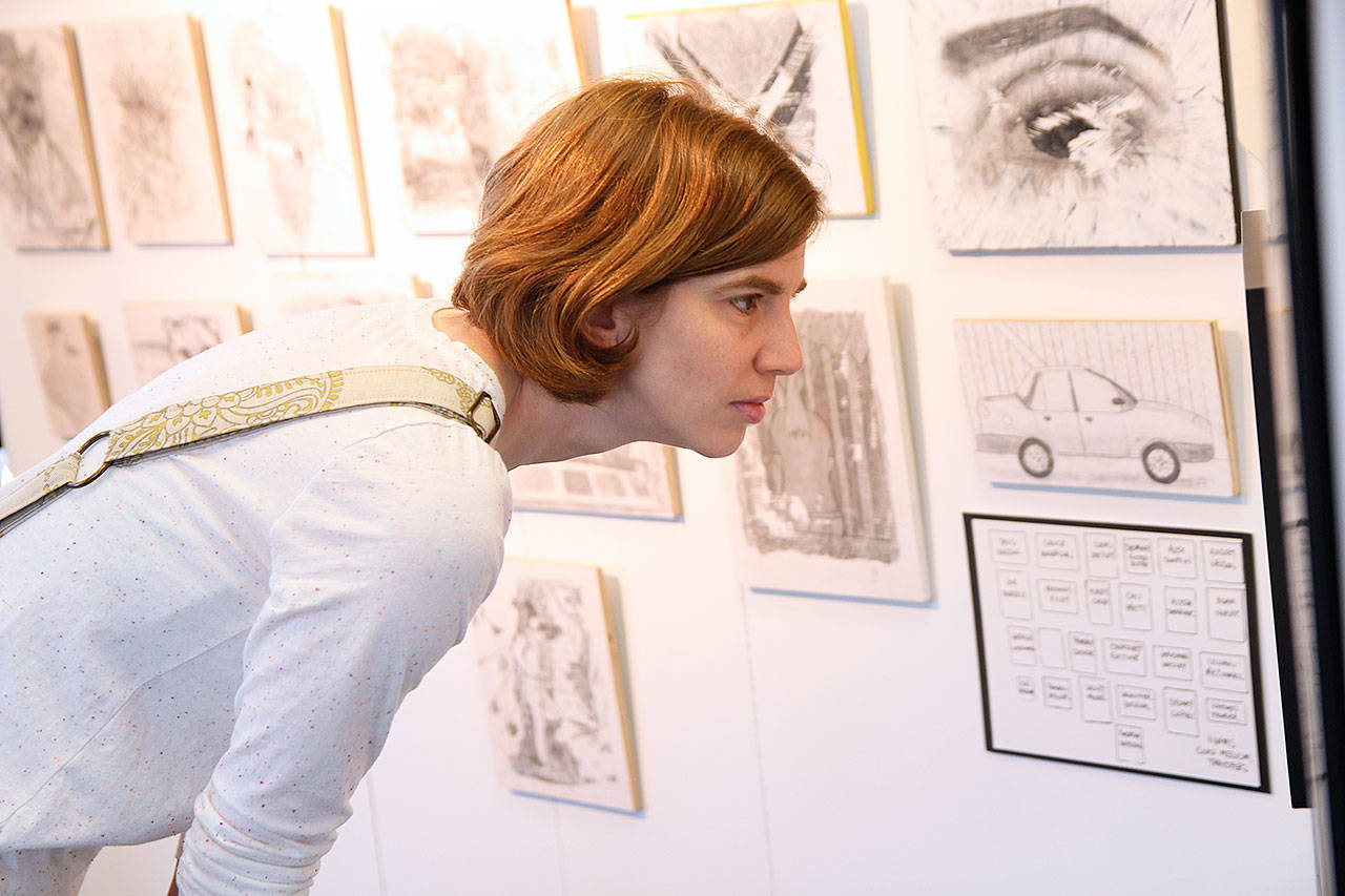 Christina Brady examines Oak Harbor Public Schools student art at a temporary gallery on Pioneer Way. Photo by Laura Guido/Whidbey News-Times