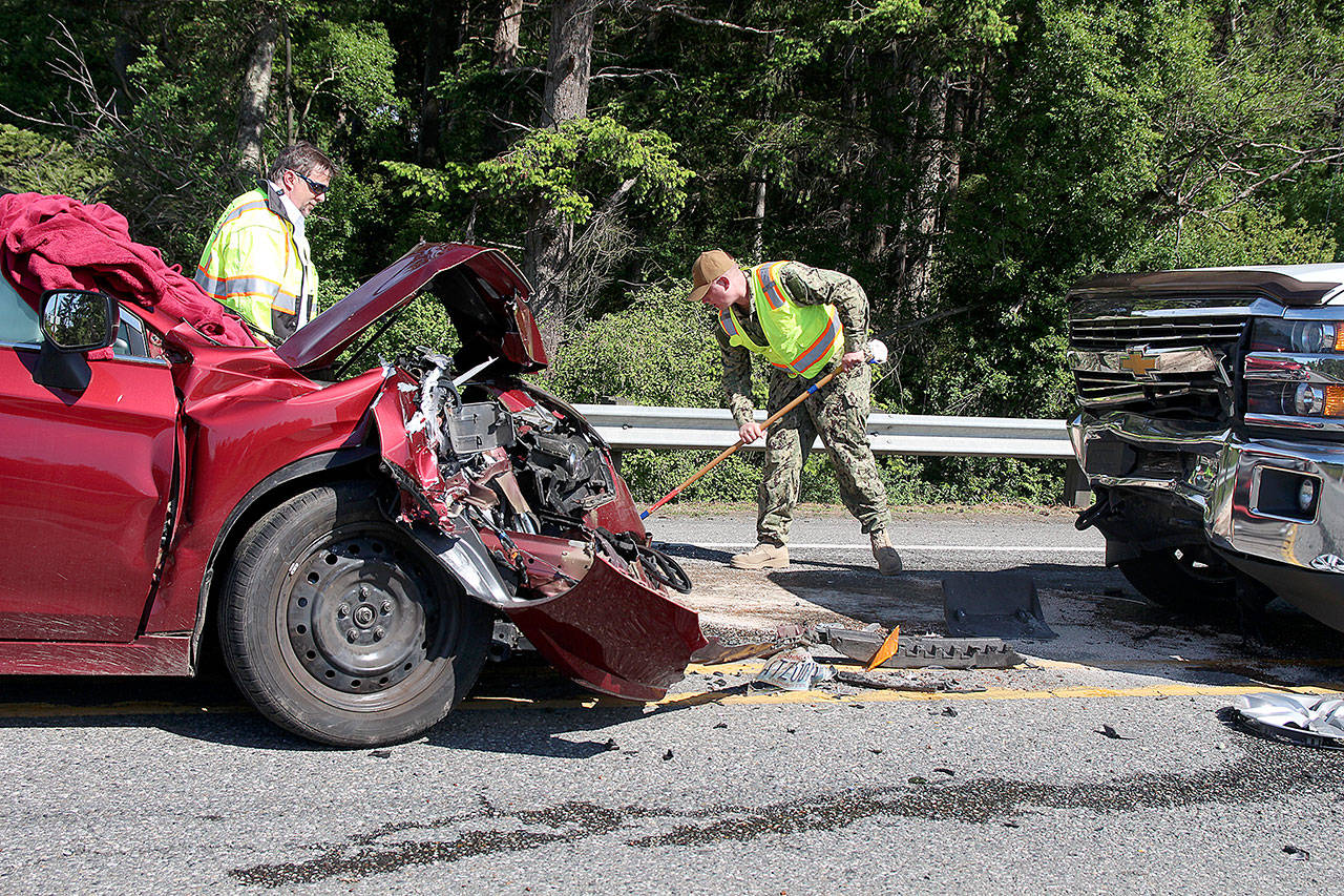 Photo by Laura Guido/Whidbey News-Times                                North Whidbey Fire/EMS Firefighter Ian Eby cleans up the scene of a head-on traffic accident Wednesday afternoon. Three people were sent to the hospital.