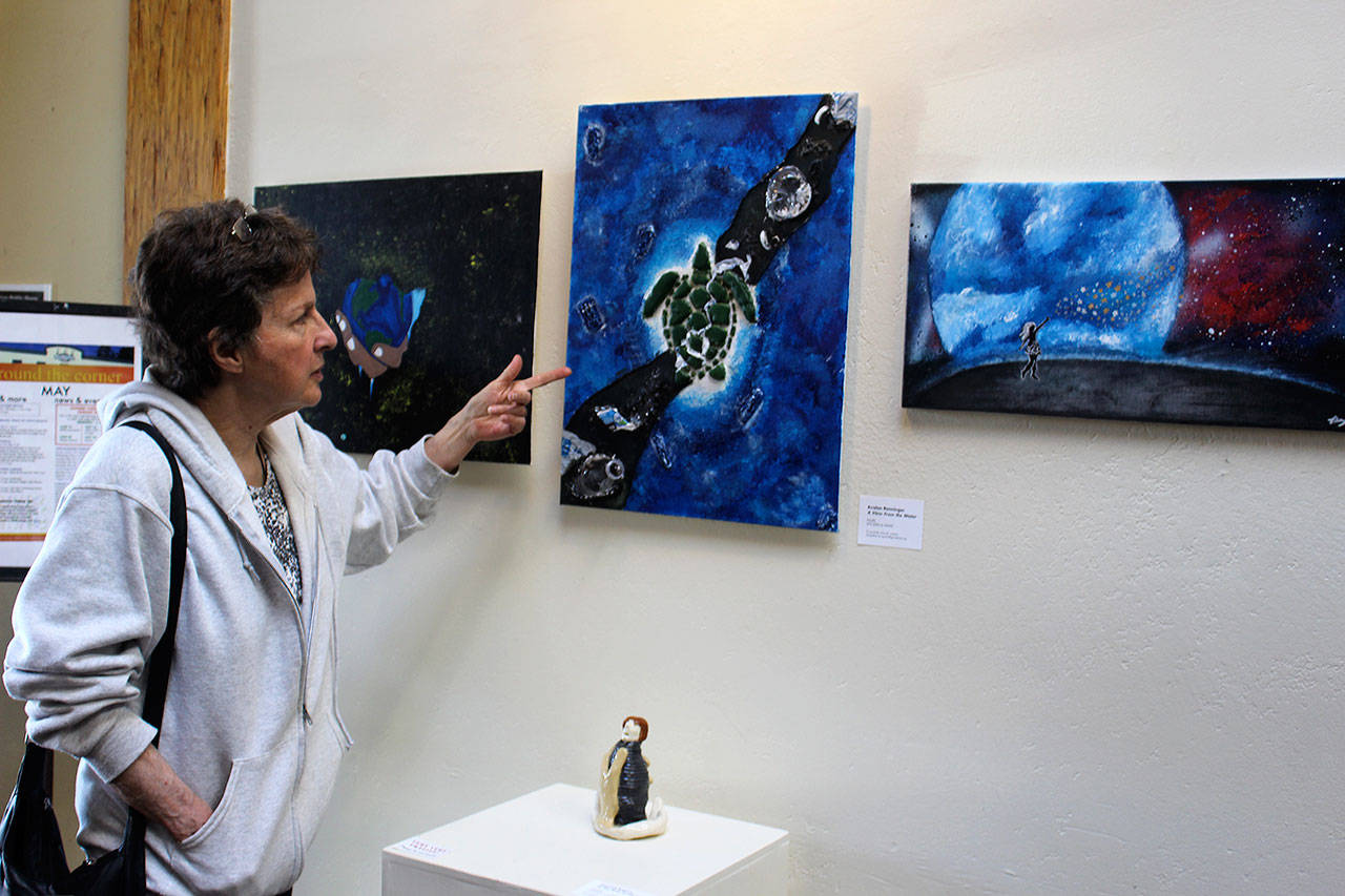 Exhibit organizer Julie Glover looks over art contributed from all of Whidbey Island’s public high schools for the exhibit, “Art with a Message.” The annual show is at Bayview Cash Store until June 9. Photo by Patricia Guthrie/Whidbey News Group