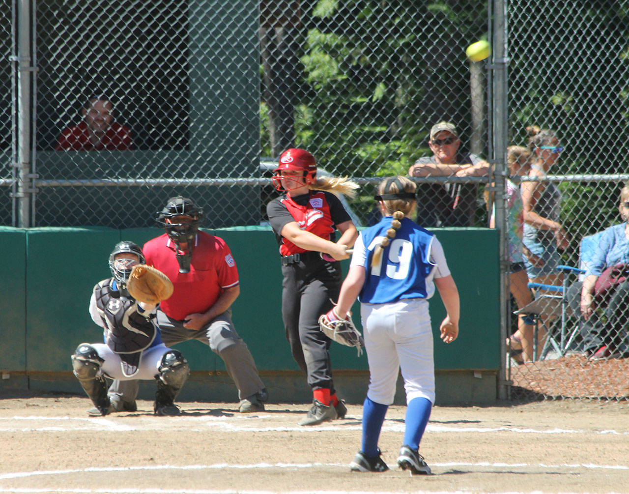 The ball flies off Madison McMillan’s bat, eventually going over the left fielder’s head for a triple. The next three photos below cover McMillan’s trip around the bases. (Photo by Jim Waller/Whidbey News-Times)