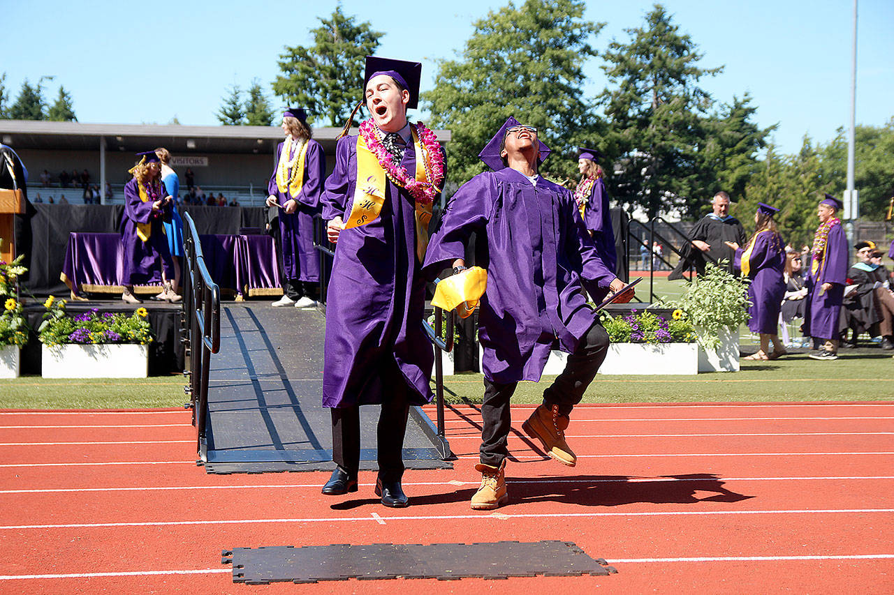 Tyler May, left, and Truth Underwood celebrate receiving their diplomas Saturday afternoon at the Oak Harbor High School graduation ceremony. Top photo, graduates toss their mortar boards in the air after Superintendent Lance Gibbon officially declared them the Oak Harbor High School graduating class of 2019. Photo by Laura Guido/Whidbey News-Times