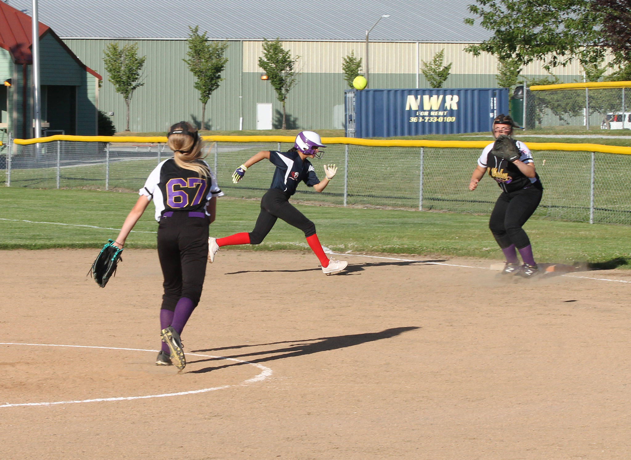 After fielding a grounder, North Whidbey pitcher Lydia Ster throws to first baseman Haylee Bingham for an out. A South Skagit runner, who started on first base, mistakenly ran back to the bag on the play before heading to second. (Photo by Jim Waller/Whidbey News-Times)