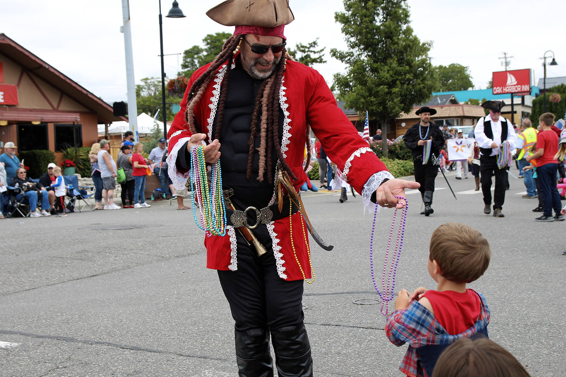 Rob Boyle of the Oak Harbor Yacht Club Buccaneers hands out beads to 3-year-old Finnigan Reilly, who was a fan of the pirate-themed parade float that made loud “booms.”