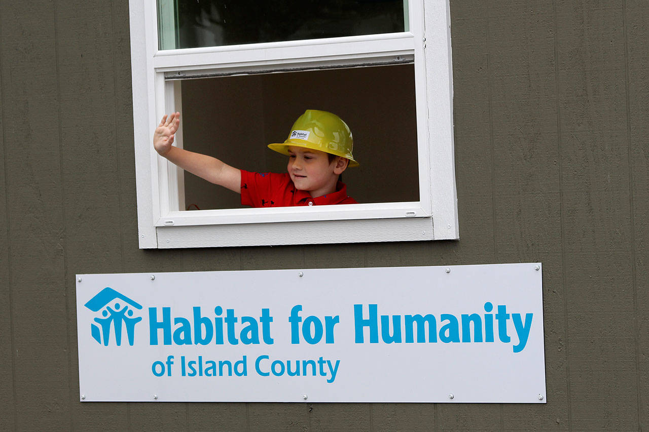 Skyler Stephen waves to the crowd in the Habitat for Humanity of Island County parade float. He is the grandson of a homebuyer.