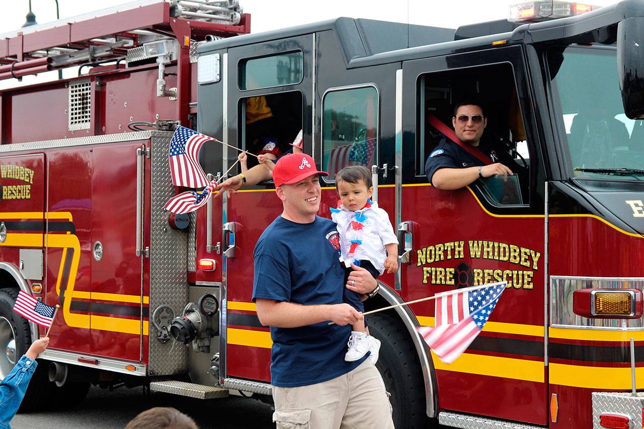North Whidbey Fire and Rescue firefighter Michael Pelzer looks out from the truck as Tom Torgerson holds his 22-month-old son, Matthew Torgerson. Monica Torgerson of NWFR said her husband volunteered to walk in the parade with their son.