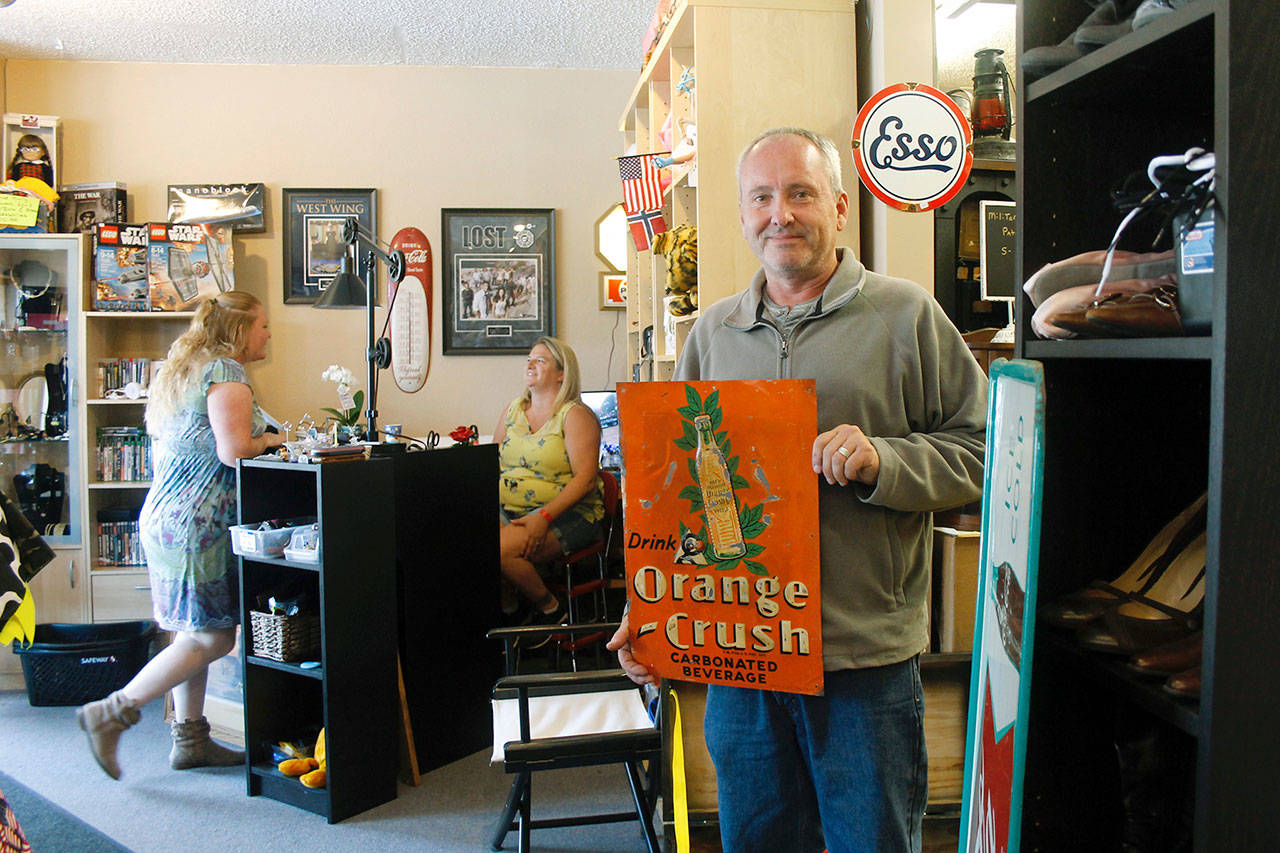 Matt Shorey holds one of his favorite items in the store, a vintage sign, as Tina Shorey talks with family member Kenzie Furman-Allen. (Photo by Maria Matson/South Whidbey-Record)