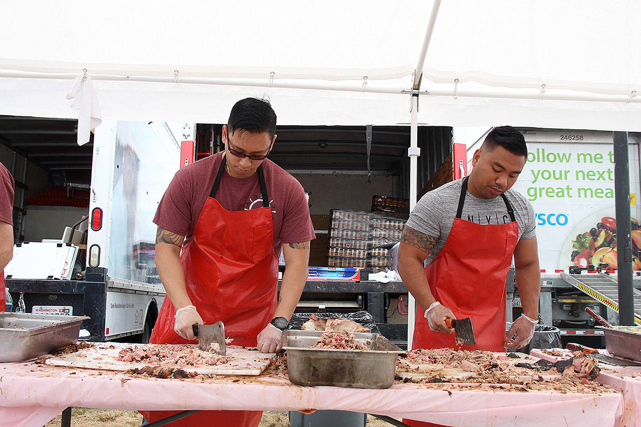 Volunteers Dat Pham, left, and Palo Salaiga from VAQ-133 and the Naval Air Station Whidbey Island Galley chop pork at Pigfest Sunday afternoon. The festival served about 3,4000 pounds of meat to around 10,000 people.