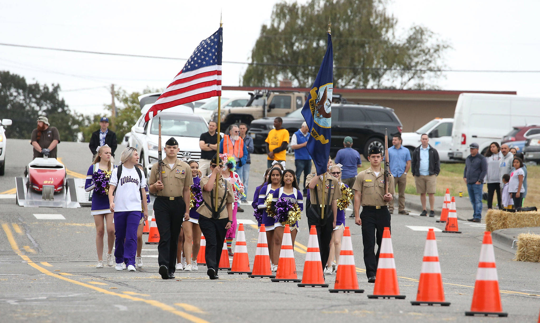 The Oak Harbor High School NJROTC colar guard and cheerleaders march down Barrington Avenue to open Saturday’s Challenge Series. (Photo by John Fisken)