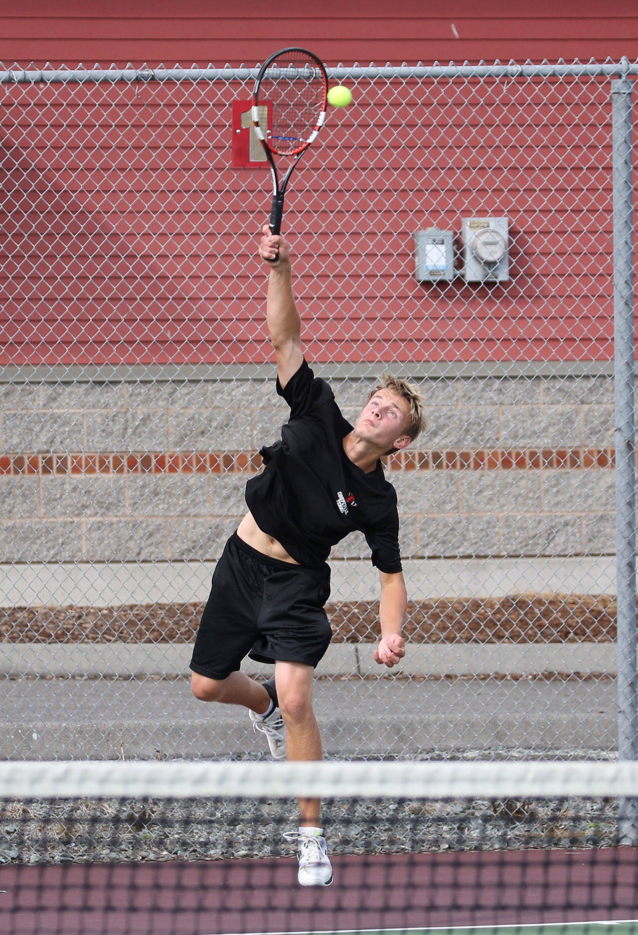 Drake Borden fires a serve in first singles. (Photo by John Fisken)