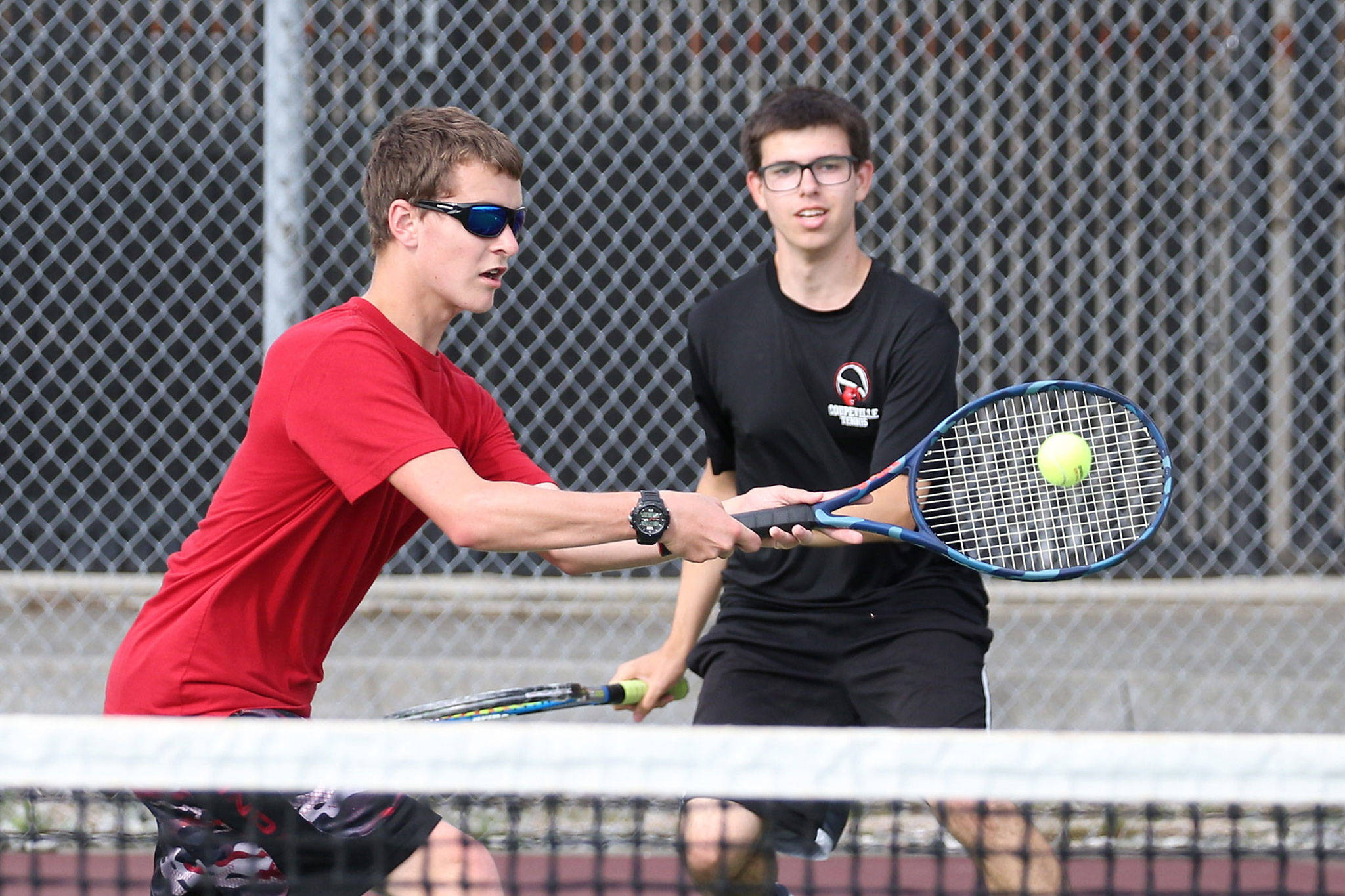 Zach Ginnings, left, returns a shot in his win in second doubles with partner Andrew Aparicio.(Photo by John Fisken)