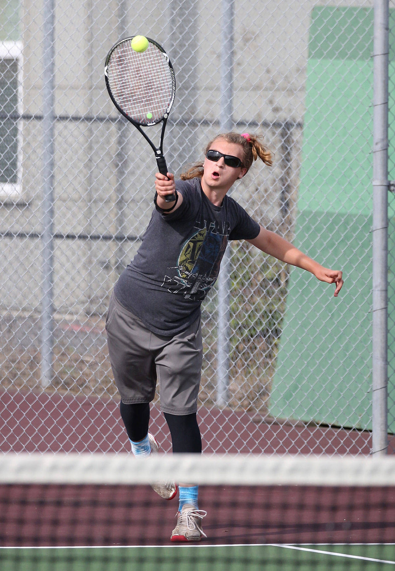 Thane Peterson unleashes a serve in third doubles.(Photo by John Fisken)