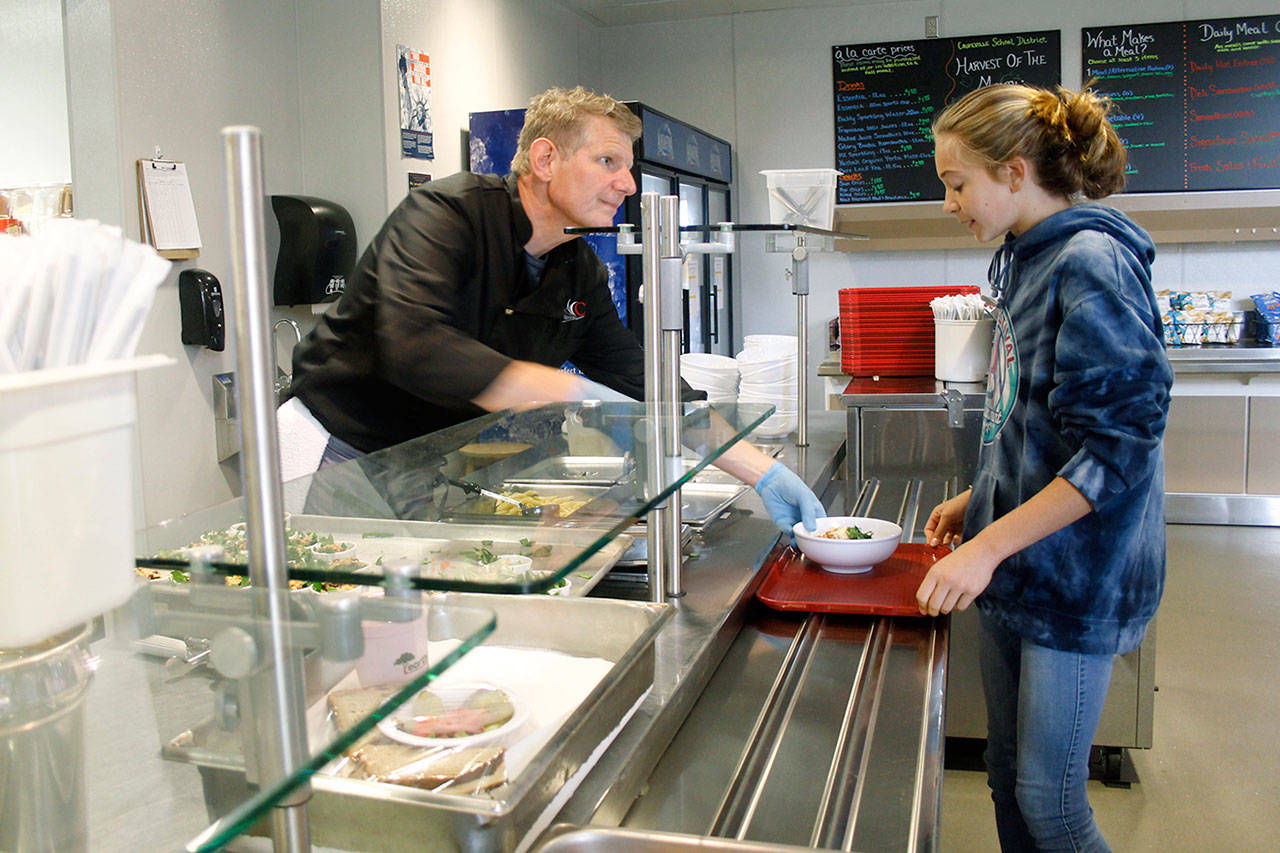 Andreas Wurzrainer serves seventh-grader Lyla Stuurmans a school lunch. Wurzrainer now works full-time at the Coupeville School District, serving and planning meals as part of the Connected Food Program. (Photo by Maria Matson/Whidbey News-Times)