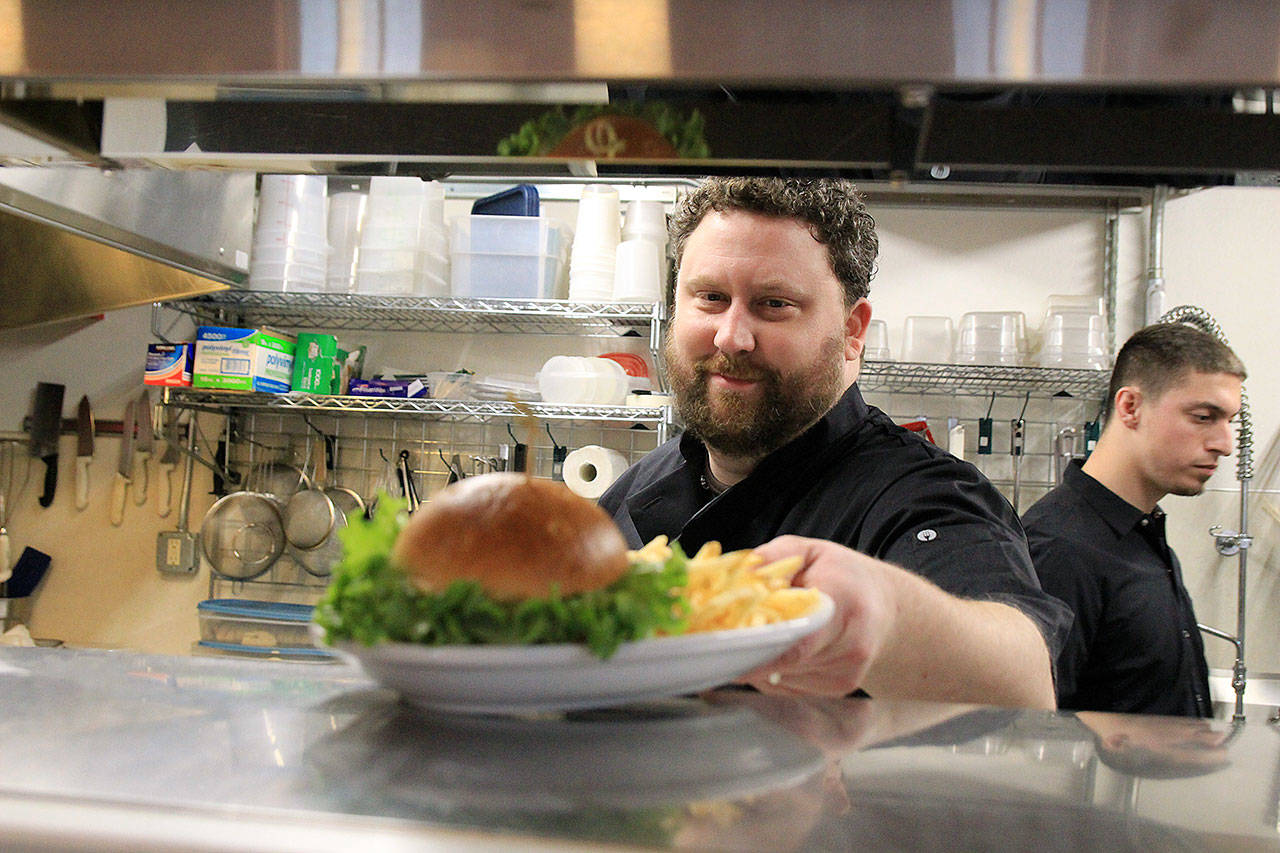 Damien Cortez, co-owner and chef at The Cove in Coupeville, serves up a “salmon sammy.” Photo by Laura Guido/Whidbey News-Times