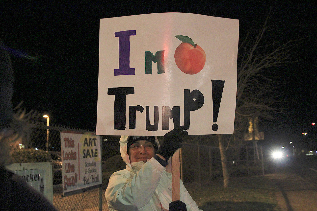 Debbie Legasse holds a sign on Main Street in Coupeville as part of a rally to support the presidential impeachment.