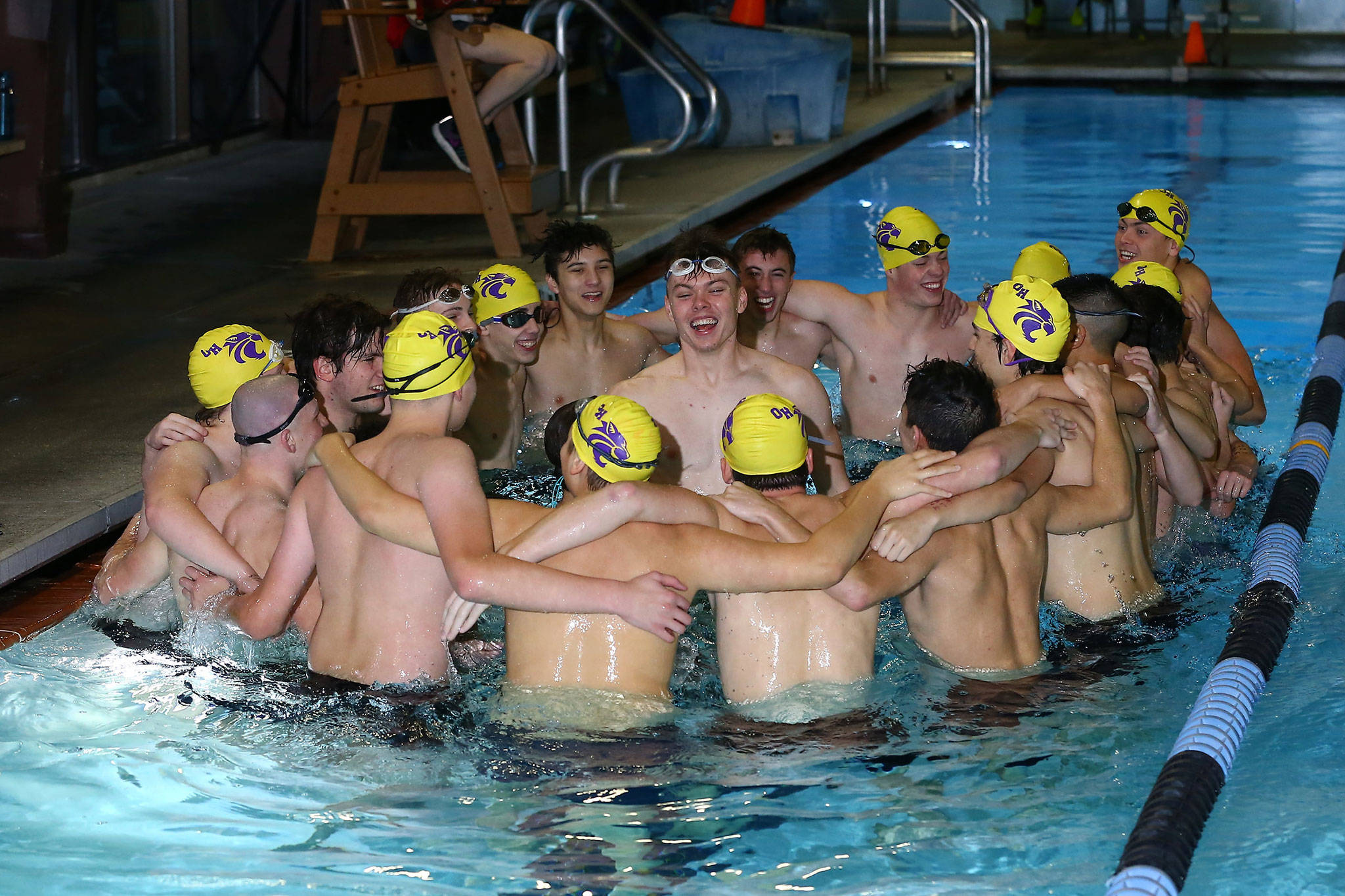 The Oak Harbor High School swim and dive team begins Thursday’s meet with a group cheer. (Photo by John Fisken)