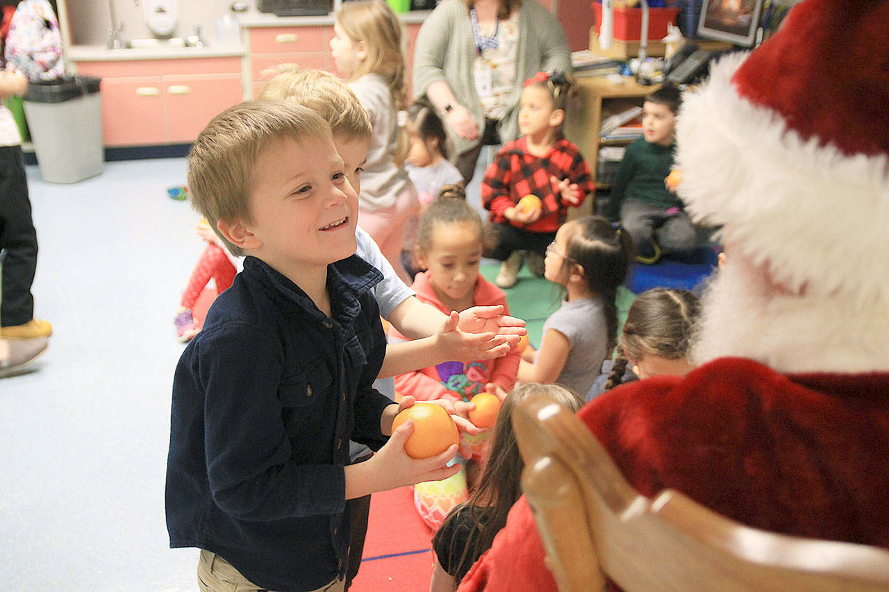 Santa gives kindergartner Isaac Hamm a nice, cold orange last Wednesday during the big man’s visit to Hillcrest Elementary School.