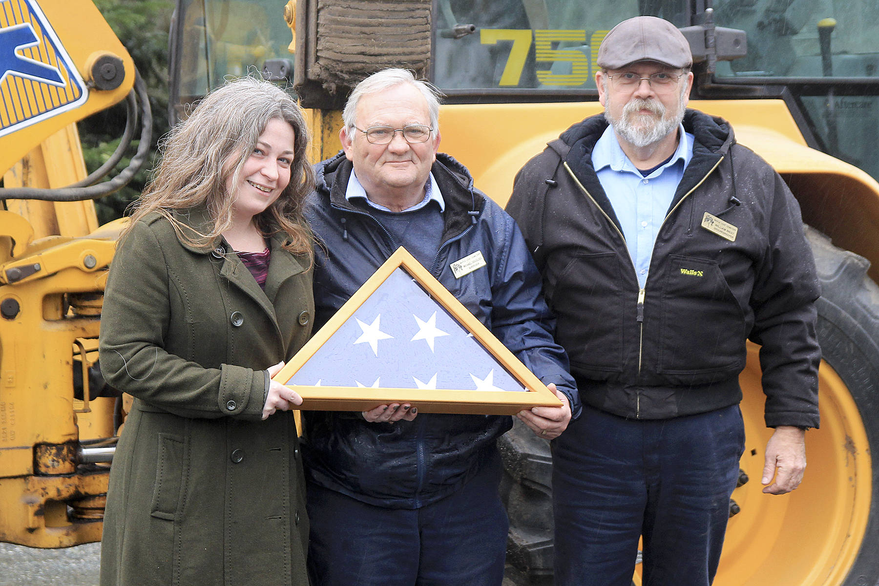 Memorial Day event organizer Kelly Davidson, Maple Leaf Cemetery Caretaker Mike Dougliss and Groundskeeper William West hold a flag that will be presented at this year’s event.