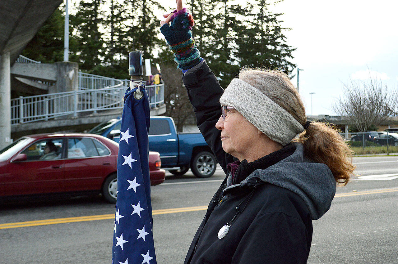 Photo by Laura Guido/Whidbey News-Times                                 Event organizer Linda Wehrman holds up the peace sign to passing cars Thursday on Highway 20 in Coupeville during an anti-war protest.