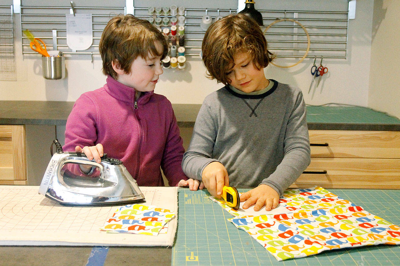 Arya Bochantin, left, irons a pattern while Rio Goette, right, cuts out patterns.