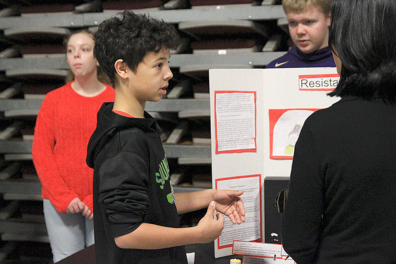 Eighth grader Andrew Williams explains the book “Resistance” to a visitor at Monday’s Holocaust Remembrance Book Exhibit at Coupeville Middle School. Photo by Laura Guido/Whidbey News-Times