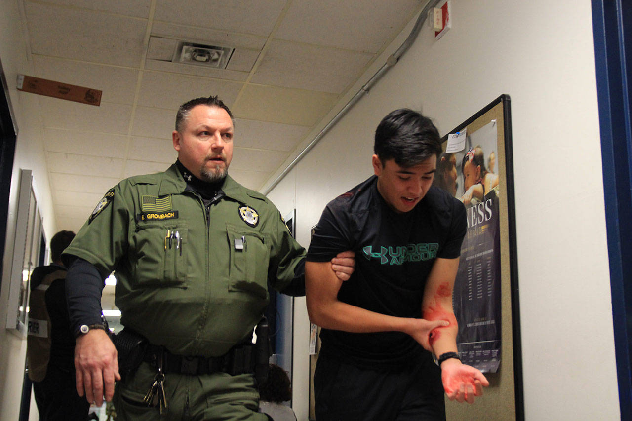 Photo by Brandon Taylor/Whidbey News-Times                                Island County Sheriff Deputy Eric Gronbach escorts a volunteer Oak Harbor NJROTC student to safety during the training exercise.