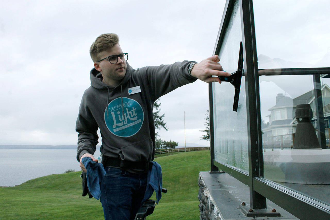 Photo by Kira Erickson/Whidbey News Group                                Business owner Oliver Hansen cleans a window at a Mutiny Bay residence on Monday.