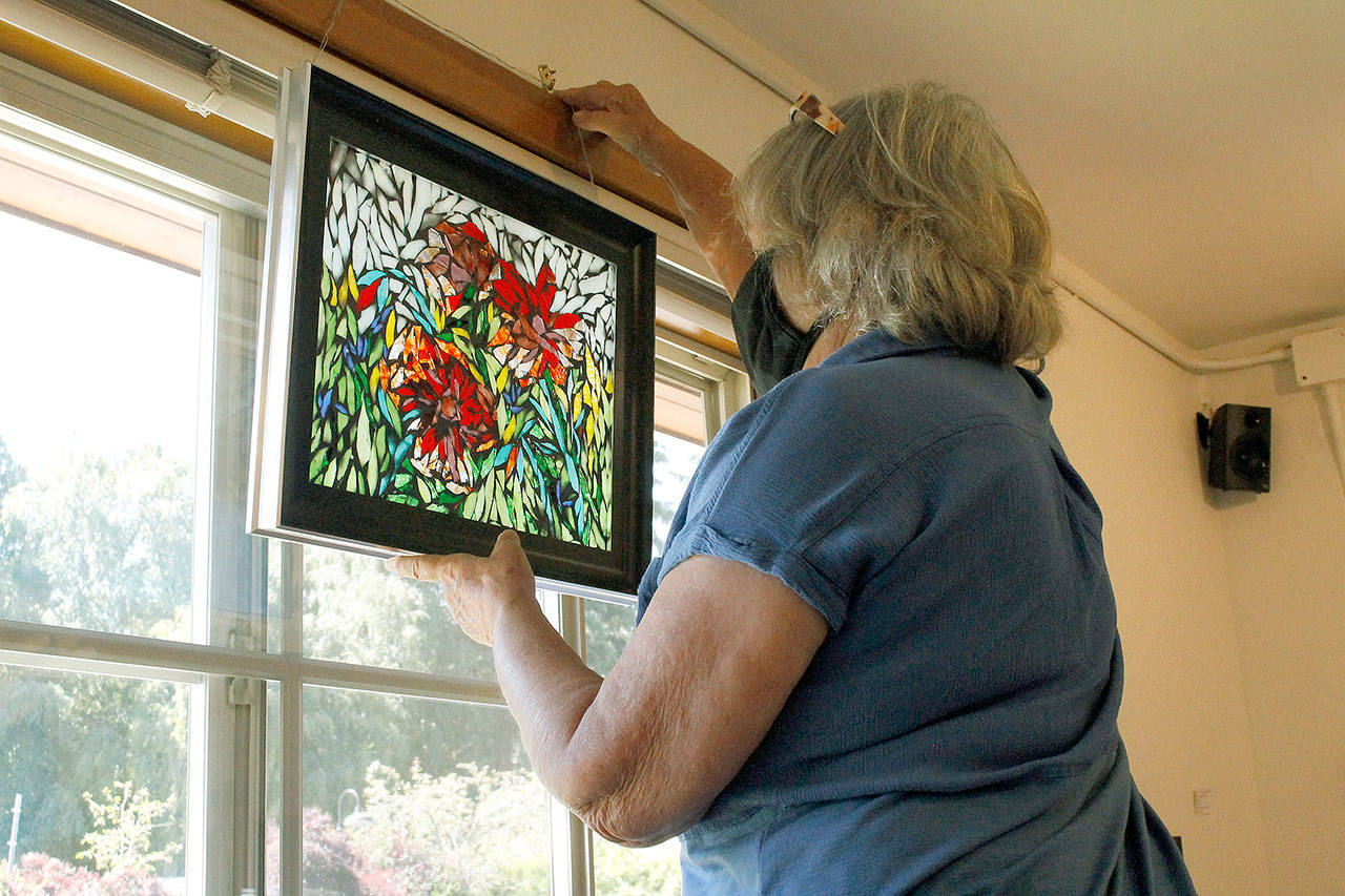Photo by Kira Erickson/Whidbey News-Times                                Artist Christine Crowell hangs a mosaic piece of hers in the window of Artworks Gallery.