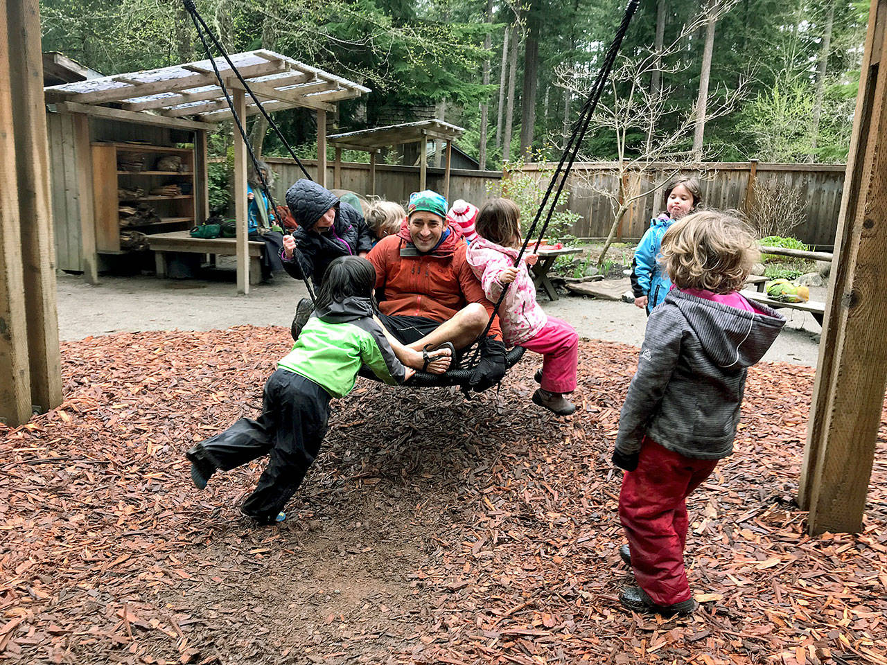 Photo by Carol Johnsen                                Teacher William Dolde with his kindergarten class on the playground swing in 2018. Outdoor playtime is a celebrated activity at the Waldorf school.