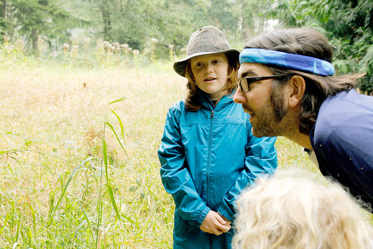 George Kyncl, 9, studies a spider with his father, Jeremy. Finding creatures is part of a nature-based curriculum. Photo by Kira Erickson/Whidbey News-Times