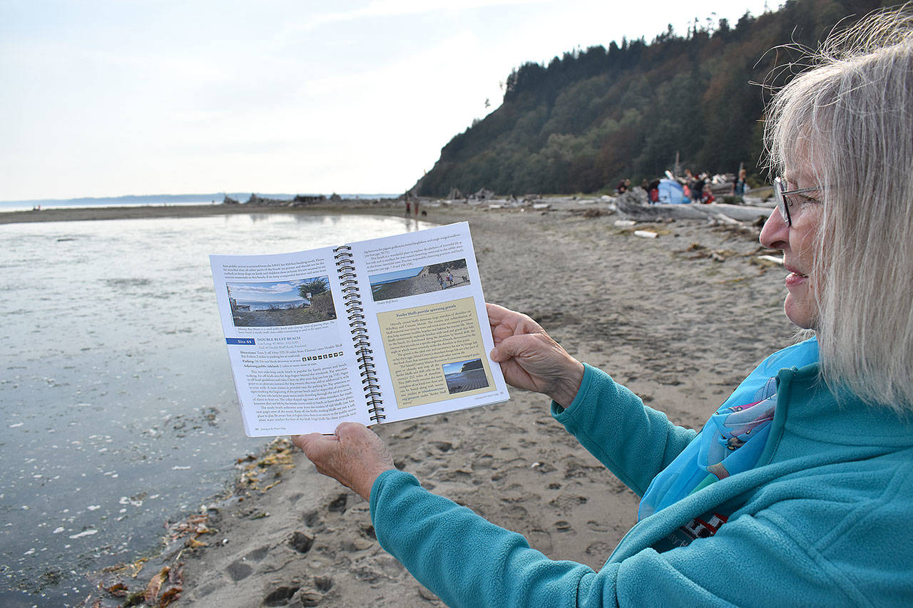 Jeanie McElwain holds the new edition of “Getting to the Water’s Edge,” a book that includes information about beach accessibility, fishing spots, natural history, species identification and more, including all of the sea creatures that can be found at Double Bluff in South Whidbey. Photo by Emily Gilbert/Whidbey News-Times