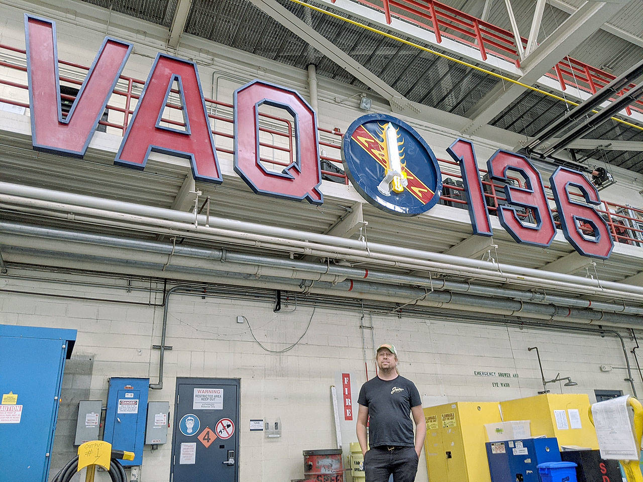 Photo provided
Langley business owner Tim Leonard stands below the growler squadron’s completed sign, which includes a sword made of neon. He helped Lt. Cmdr. Ryan Salcido of VAQ-136 to build the sign.