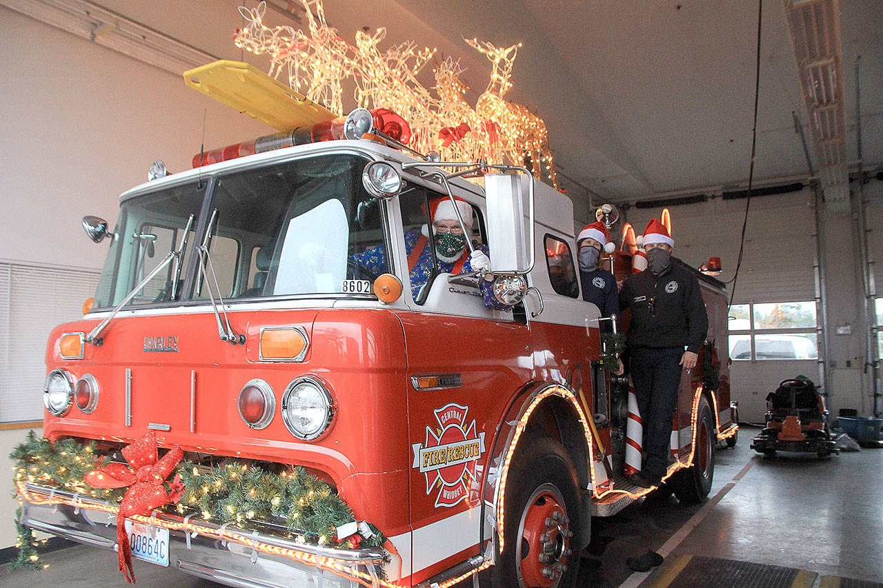 Santa and his elves, Jen Porter and Dalton Martin, have begun decorating Central Whidbey Fire and Rescue’s Santa Mobile, which begins making the rounds on Dec. 7. Photo by Emily Gilbert/Whidbey News-Times