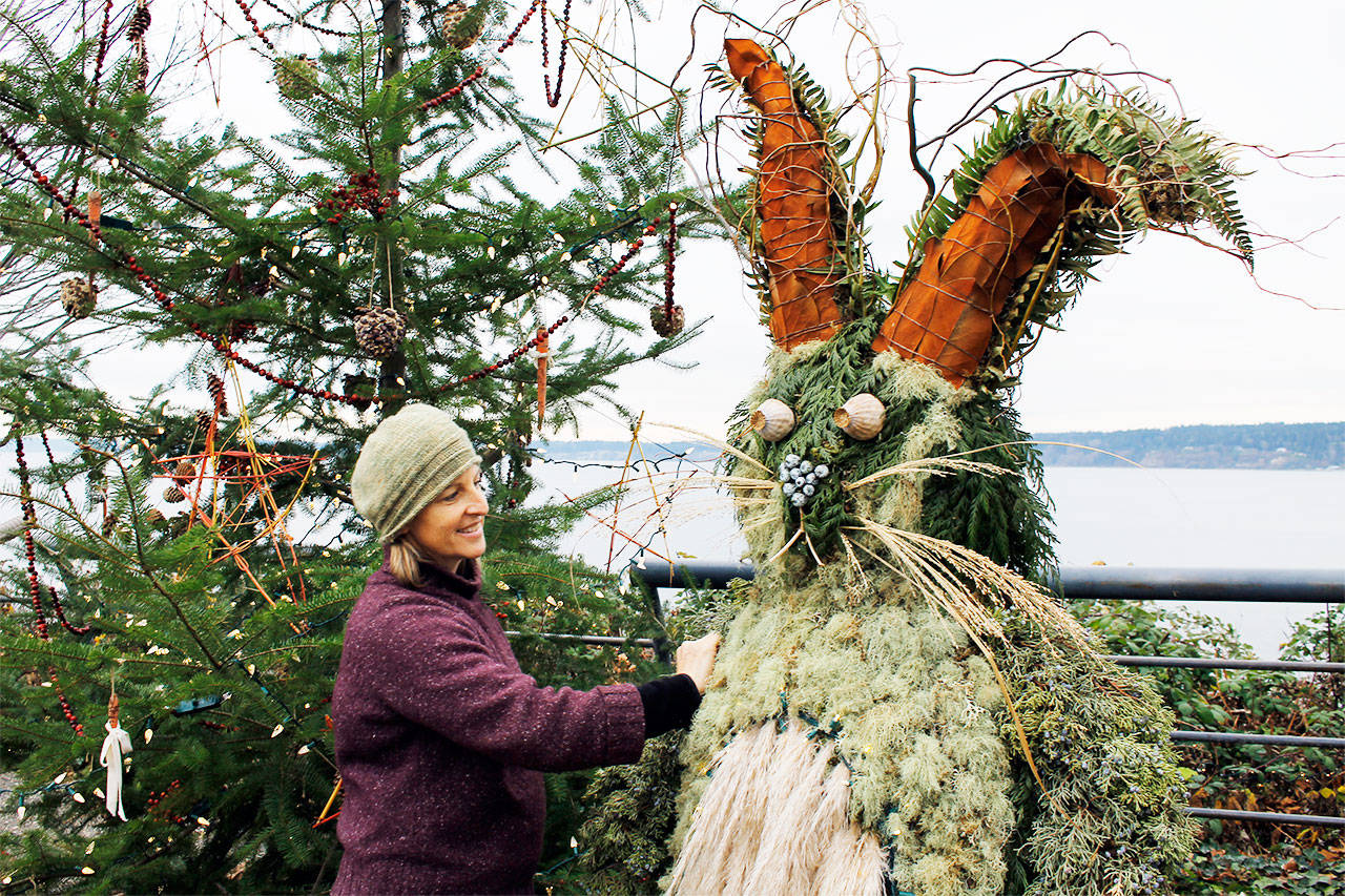Tobey Nelson, a floral designer who brought Juniper B. Bunny to life, makes adjustments to her creation on Thursday. The big green rabbit is part of an eco-friendly, holiday-themed installation in Langley. Juniper can be found next to his Christmas tree at Boy and Dog Park on First Street. Photo by Kira Erickson/South Whidbey Record