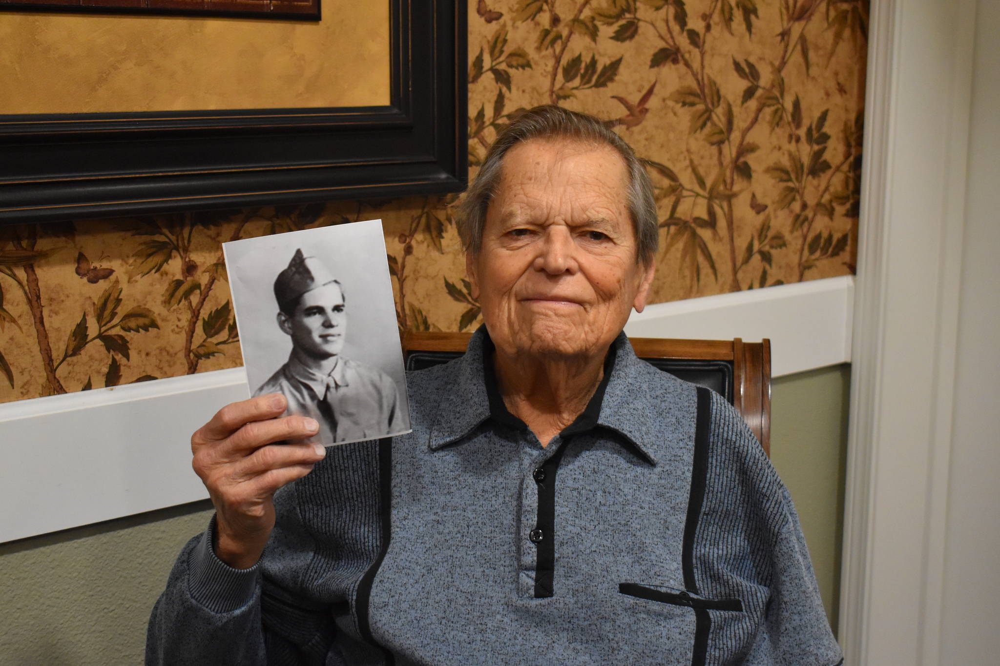 Frank Burns, now in his 90s, holds a photo of himself when he was still in training with the U.S. Army. Burns fought in the Second World War and was interviewed by Rishi Sharma recently about his experience. Photo by Emily Gilbert/Whidbey News-Times