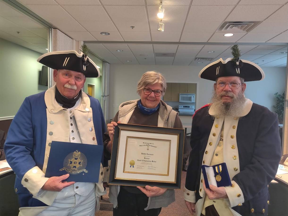 Color Guard Capt. Mike Hutchins, at left, and John Kraft present the Sons of the American Revolution Bronze Good Citizenship Medal to Bobbi Lornson, center. (Photo by Teresa Addison)